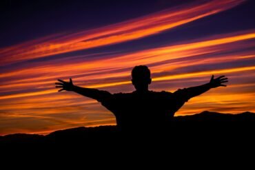 silhouette of man raising hands sideward