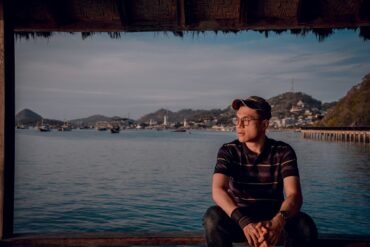 a man sitting on a dock looking out at the water