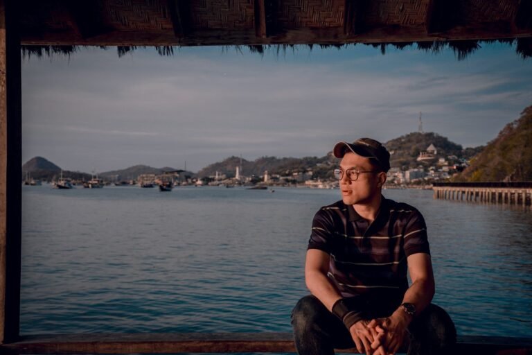 a man sitting on a dock looking out at the water