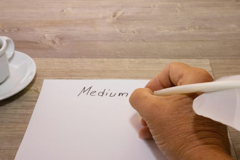 A person writing on a piece of paper next to a cup of coffee